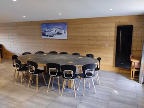 A conference room with a round table, black chairs, wooden panel walls, and a painting of a snowy mountain. - Renovated apartment near slopes with wellness area and parking (La Plagne Montchavin Les Coches)