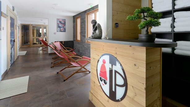 Ein Empfangsbereich mit Holztresen, einer Topfpflanze und einem an der Wand befestigten Handtuchhalter.