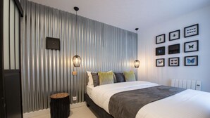 A modern bedroom with a bed, a wall-mounted light fixture, and framed pictures. - Out of Africa, 4BR/3BA, 8 people (París)