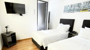 Habitació d'hotel amb dos llits, televisió, escriptori i porta.
