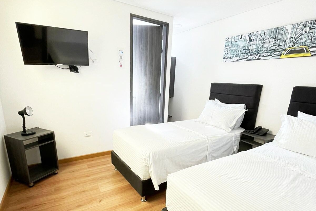 Habitació d'hotel amb dos llits, televisió, escriptori i porta.