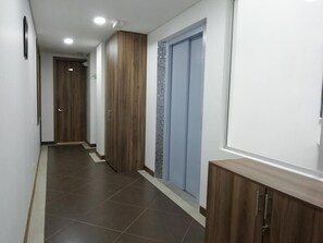 A hallway with a wooden door, a blue door, and a tiled floor. - Hotel Portal de los Andes (Bogotá)