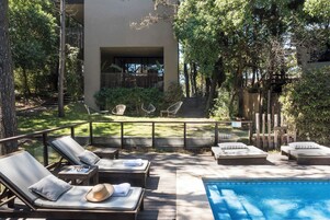 A poolside area with lounge chairs, a small table, and a staircase leading to an upper level.