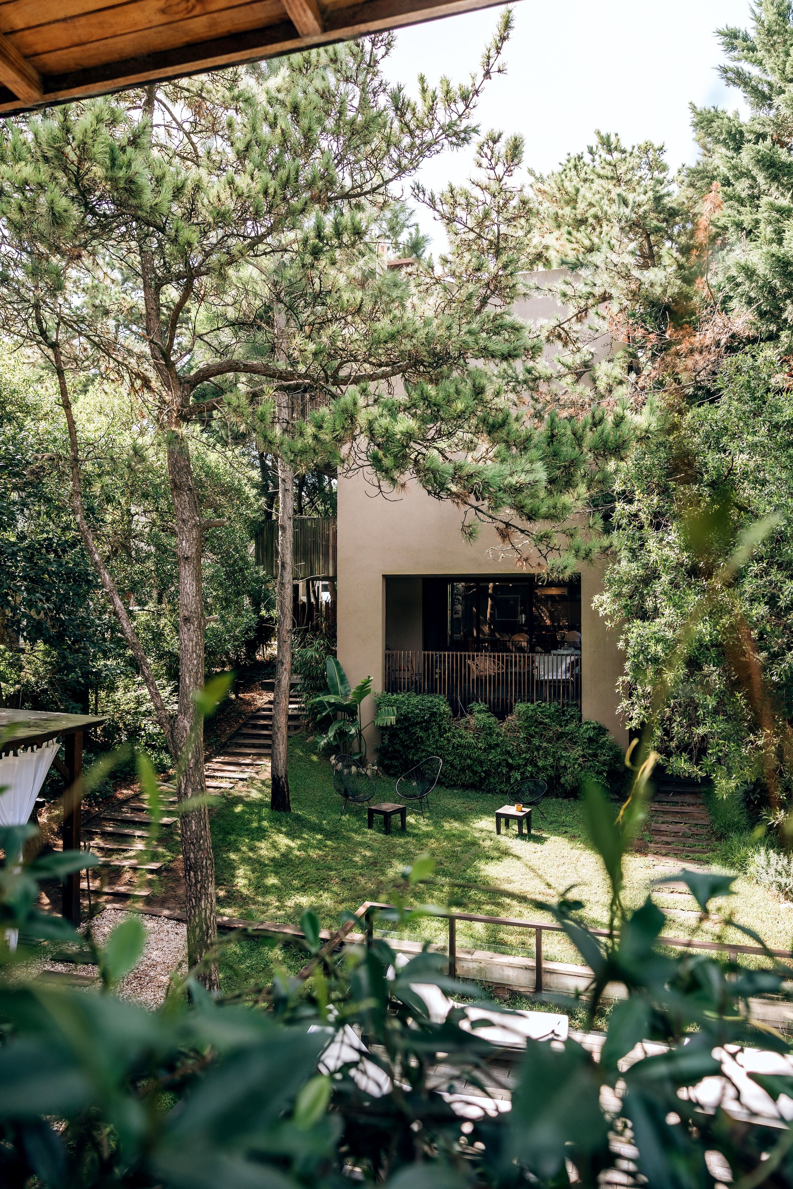 Un jardín con un porche de madera, un camino empedrado y un edificio con un ventanal grande.