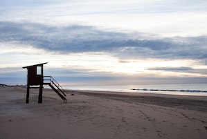A lifeguard tower on a beach with a cloudy sky.