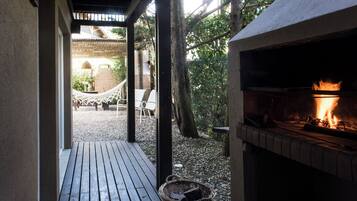 Un patio exterior con una chimenea, un deck de madera y una hamaca.
