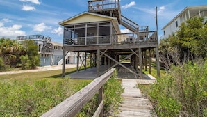 A wooden structure with a glass enclosure, a wooden staircase, and a wooden deck leading to it.