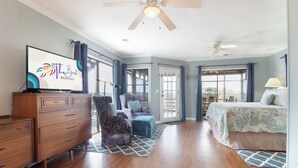 A spacious bedroom with a bed, a dresser, a chair, and a television displaying 'The Best Rentals' logo.
