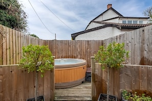 A wooden deck with a hot tub and potted plants.