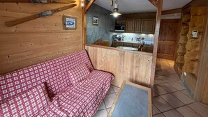A cozy cabin interior with a wooden bench, a kitchenette, and a stone wall. - Quiet 2-bedroom apartment, quick access to slopes, Les Saisies (Les Saisies)