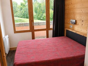 A room with a bed, a window with a view of greenery, and a wooden wall. - Bright renovated apartment - Near slopes, pets allowed (La Plagne Montchavin Les Coches)