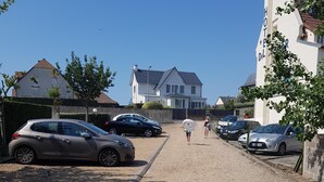 Ein Schotterweg führt zu einem Hotel, das auf beiden Seiten mit parkenden Autos gesäumt ist.