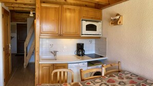 A compact kitchen with wooden cabinets, a microwave, and a coffee maker.