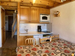 Una cocina compacta con armarios de madera, un microondas y una cafetera.