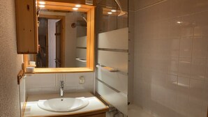 A bathroom with a white sink, a mirror, and a shower.