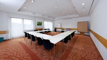 A conference room with a long table, chairs, a whiteboard, and a projector screen.