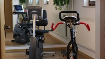 Un gimnasio con equipo de ejercicios, incluyendo una bicicleta estática y una máquina elíptica.