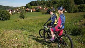To personer på cykler i en græsmark med huse i baggrunden.