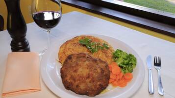 Un plato con comida, una copa de vino tinto y una servilleta doblada sobre una mesa.