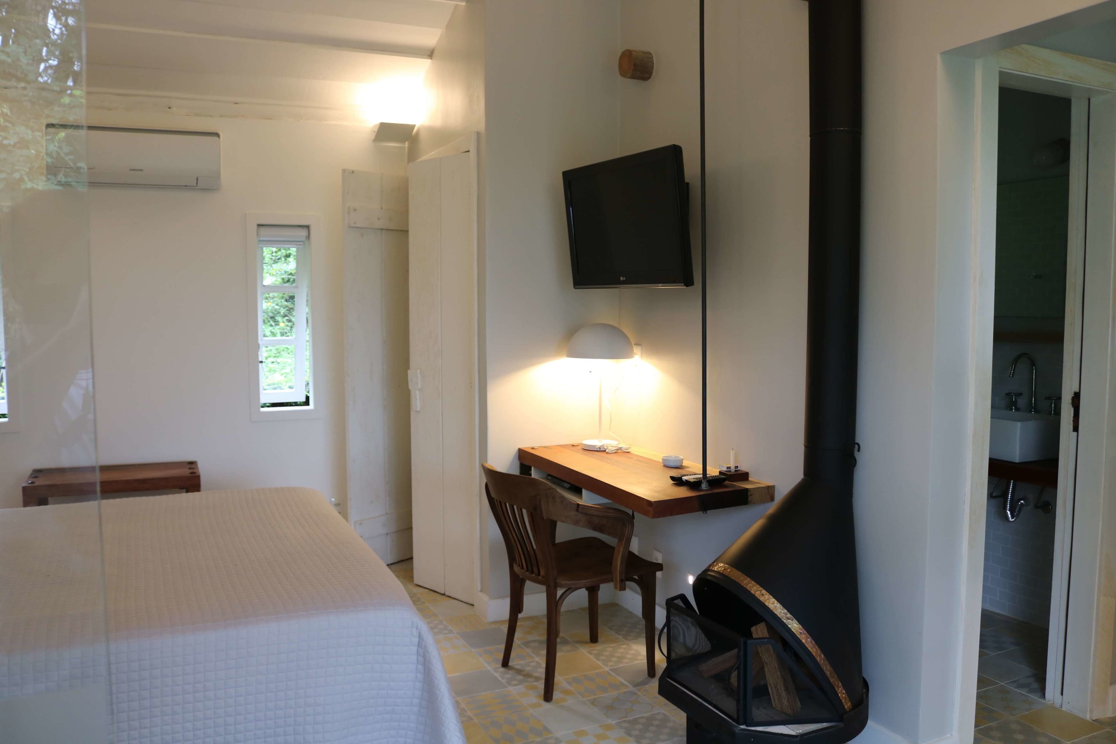 Un dormitorio con cama, escritorio, silla, televisor y chimenea.