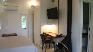 Un dormitorio con cama, escritorio, silla, televisor y chimenea.