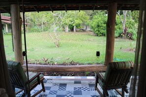 A covered patio with two wooden chairs and a checkered floor.
