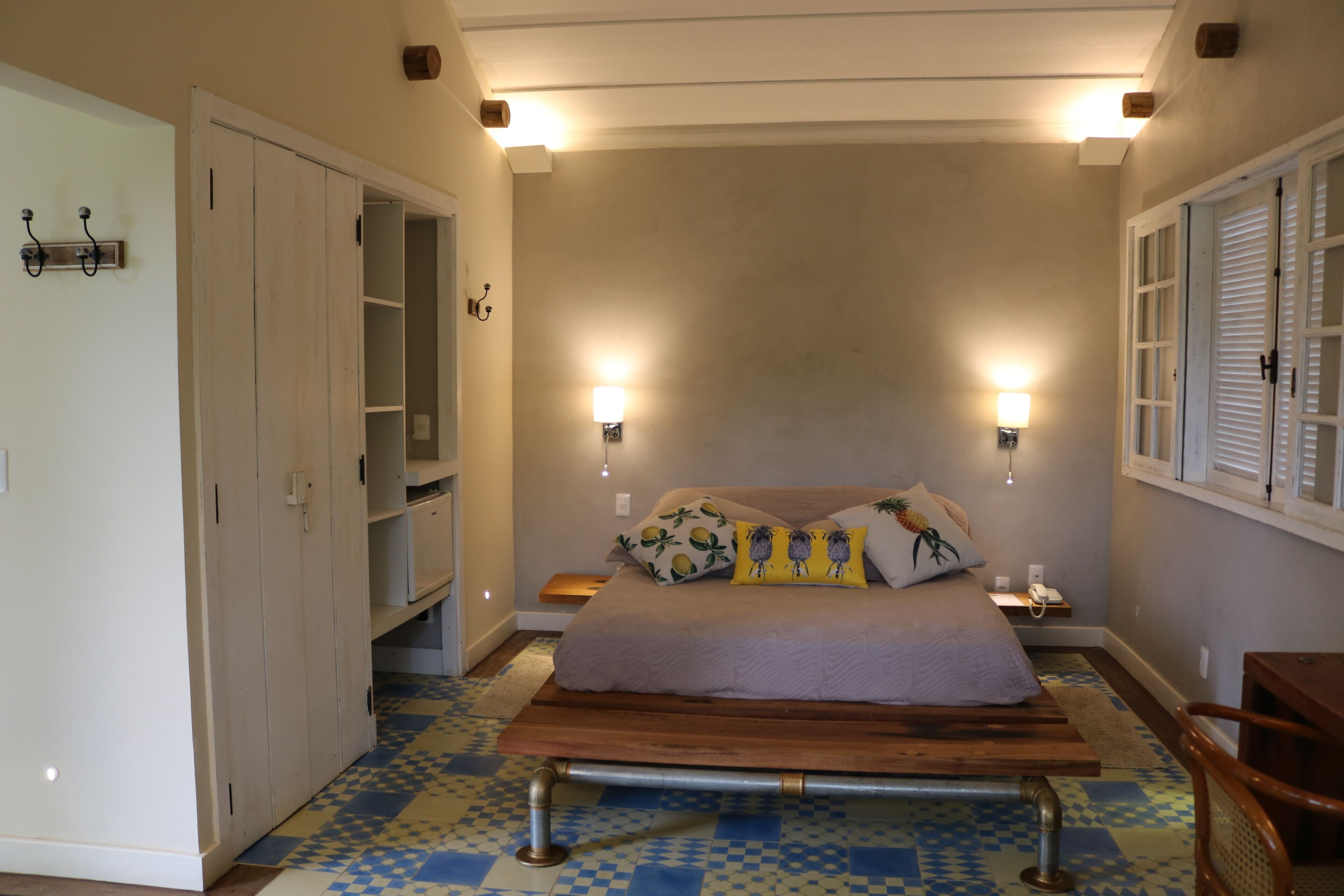 A bedroom with a bed, bedside lamps, a wooden bench, and a wardrobe.