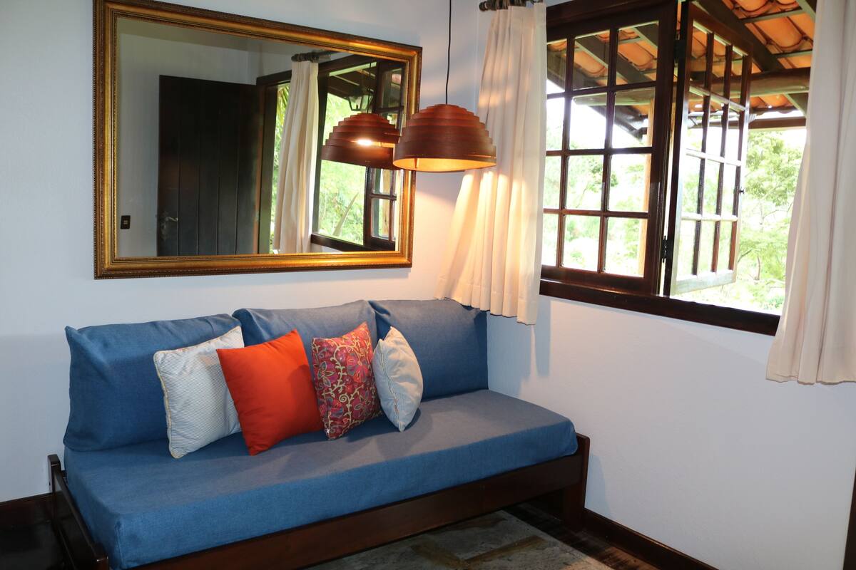 A blue sofa with multiple cushions, a large mirror, and two pendant lights.