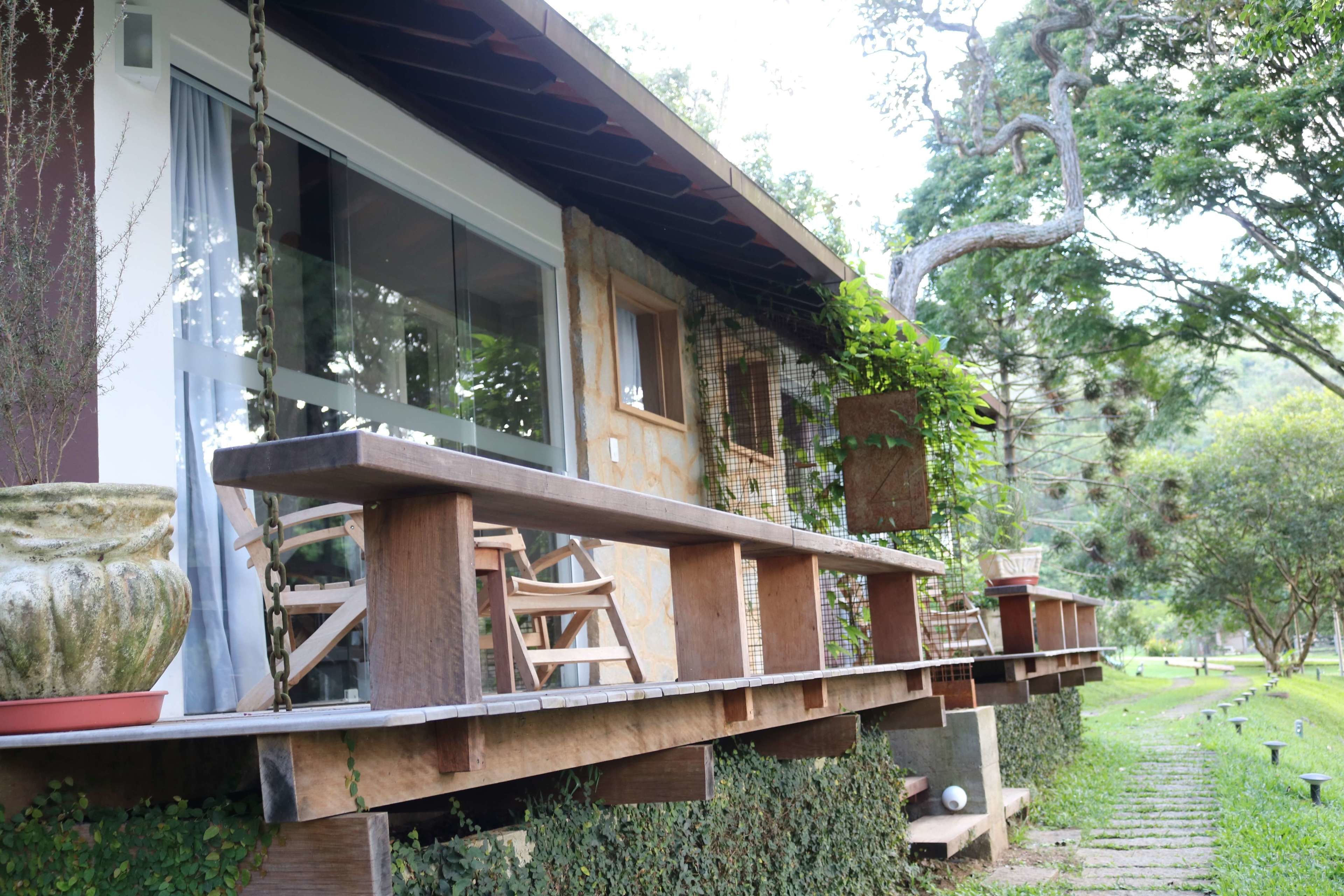 Una terraza de madera con una jardinera de piedra, una escalera y una barandilla que se extiende desde un edificio.