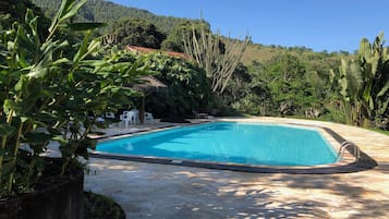 Alberca techada, alberca al aire libre y sombrillas en la alberca