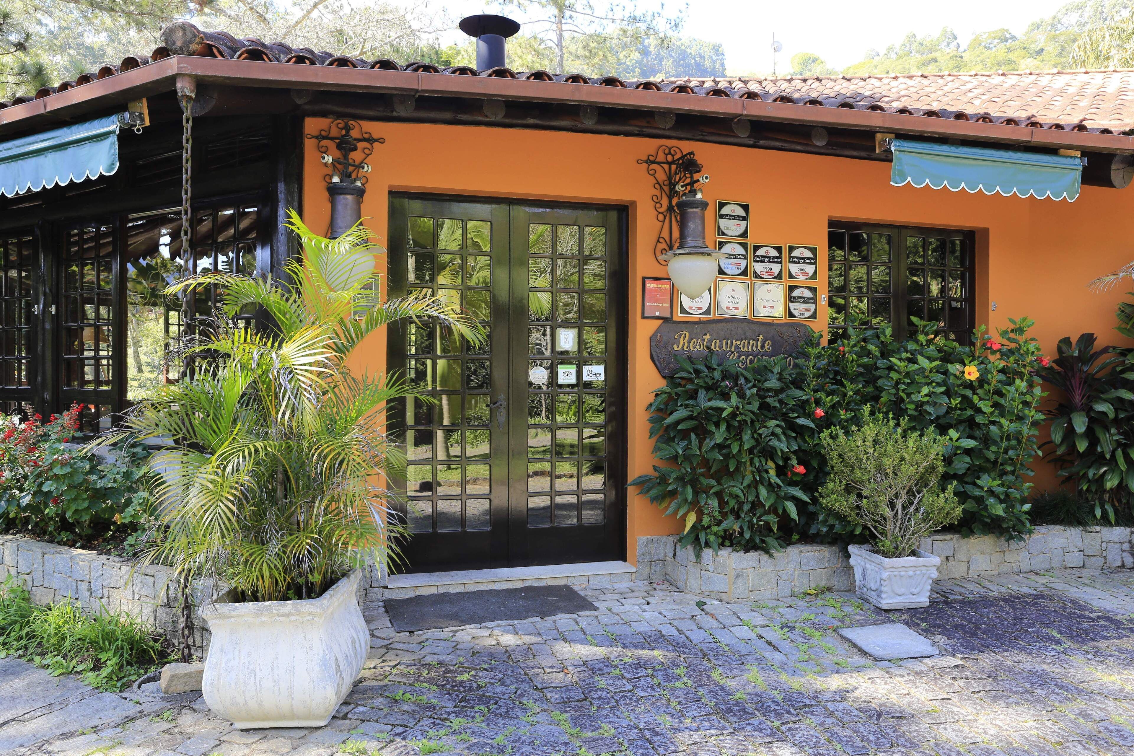 A restaurant with a tiled roof, a black door, and a signboard.