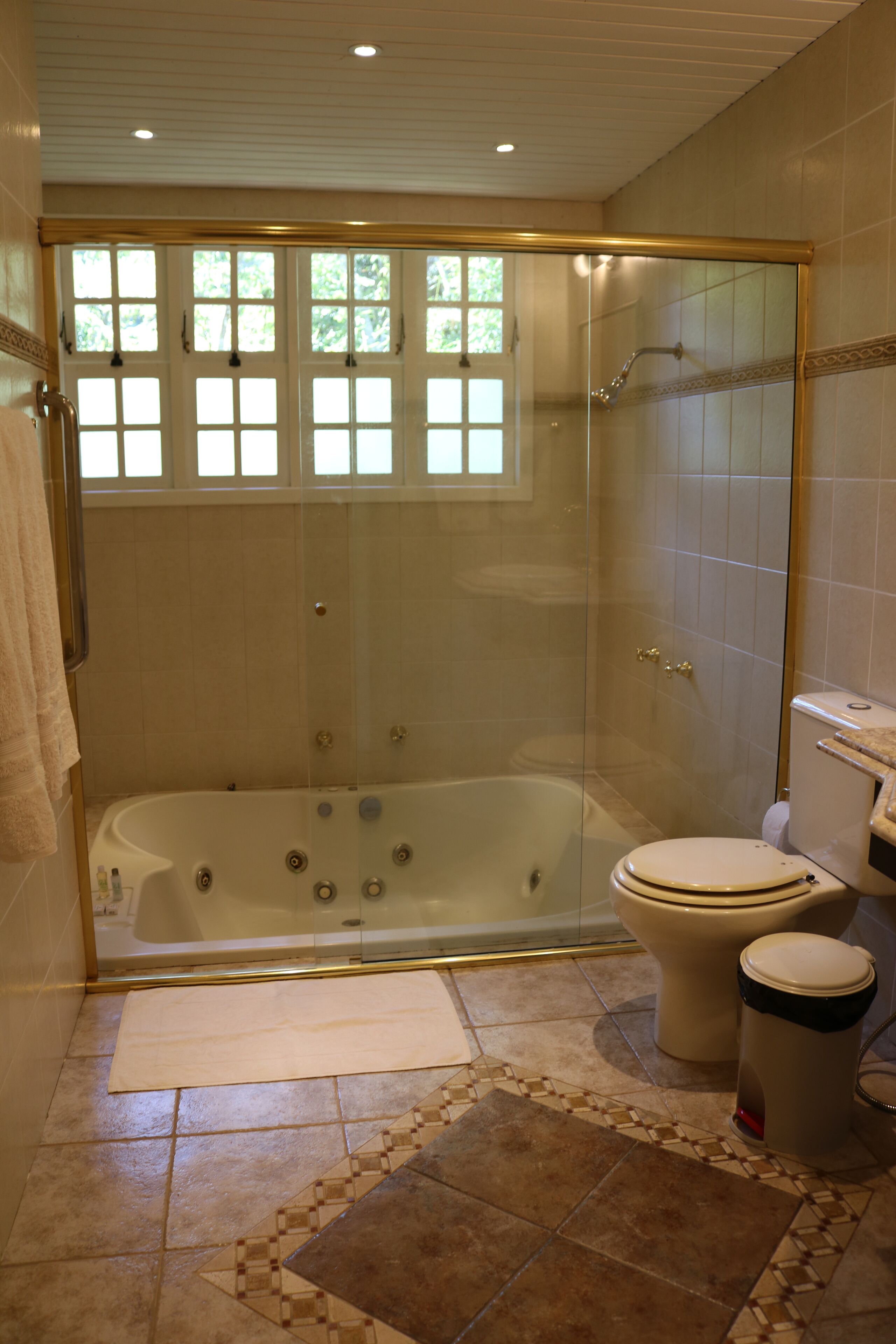 Un baño con ducha de vidrio, bañera y retrete.