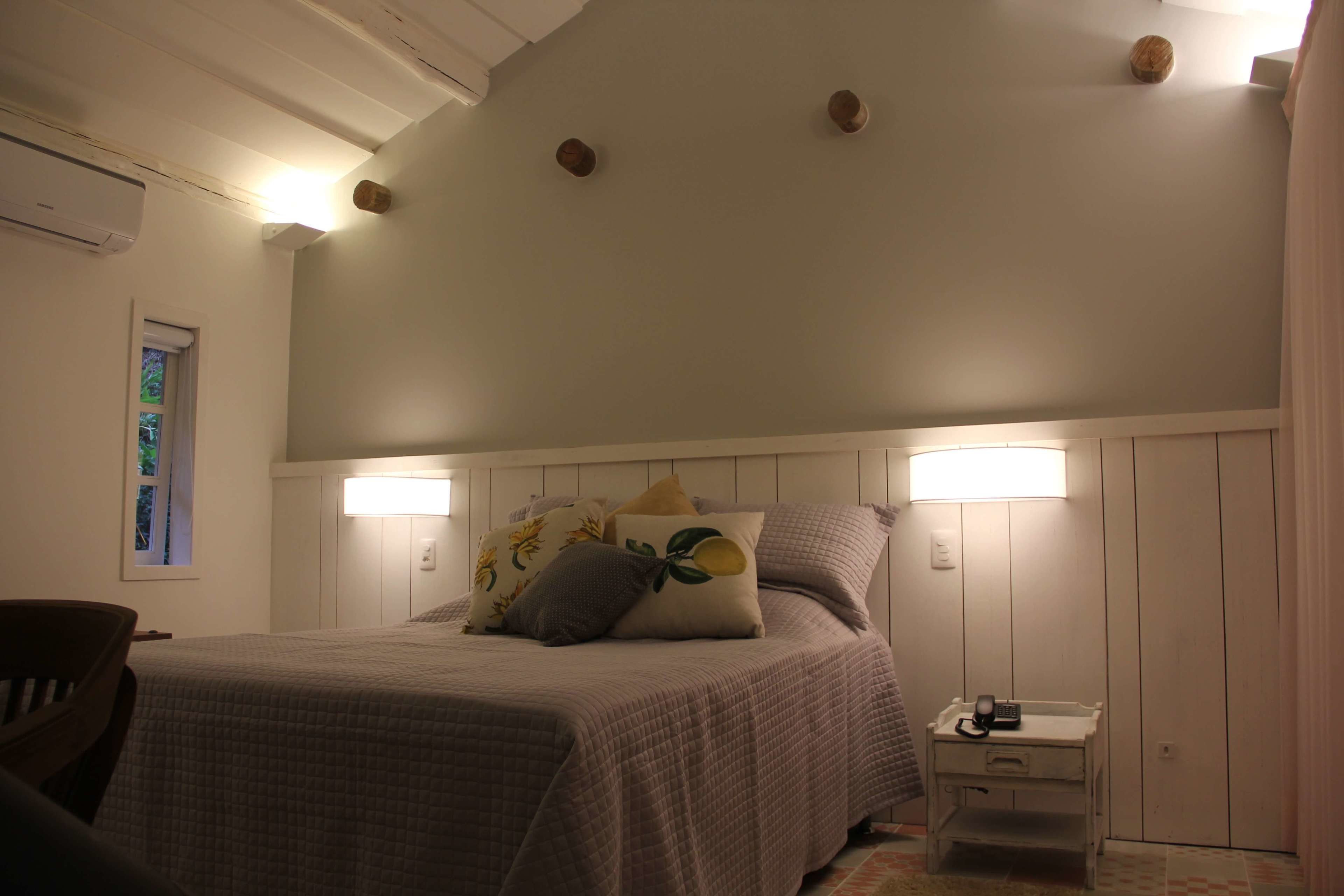 A bedroom with a bed, bedside lamps, a nightstand, and a window with a view.