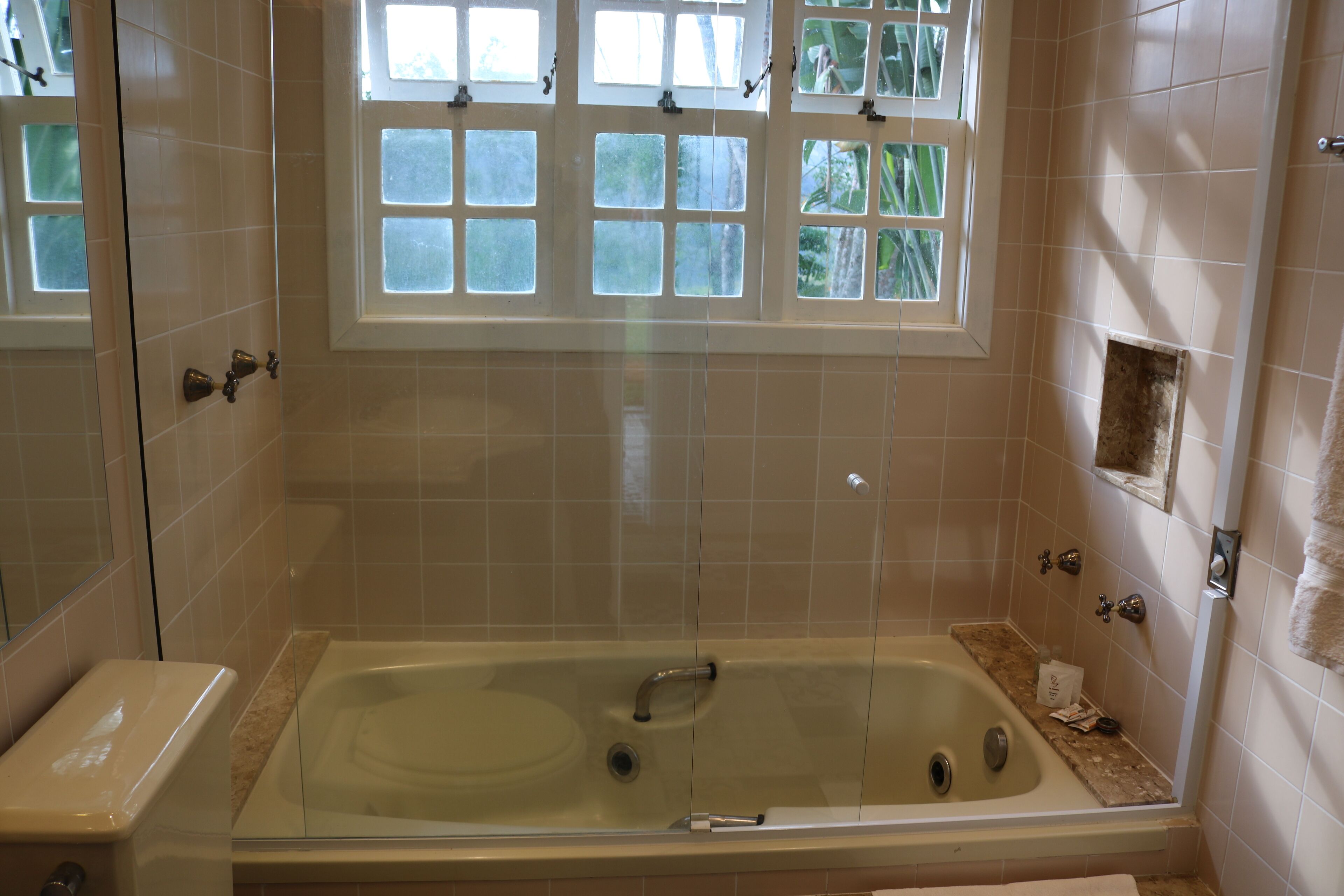 A bathroom with a bathtub, a window with frosted glass, and a towel rack.