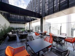 Enjoy the city view from this outdoor terrace with tables, chairs, and comfortable seating.