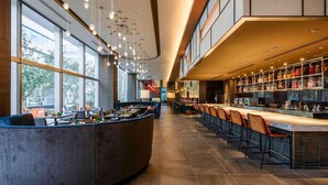 A modern bar area with a curved counter, seating, and a view of the outdoors.
