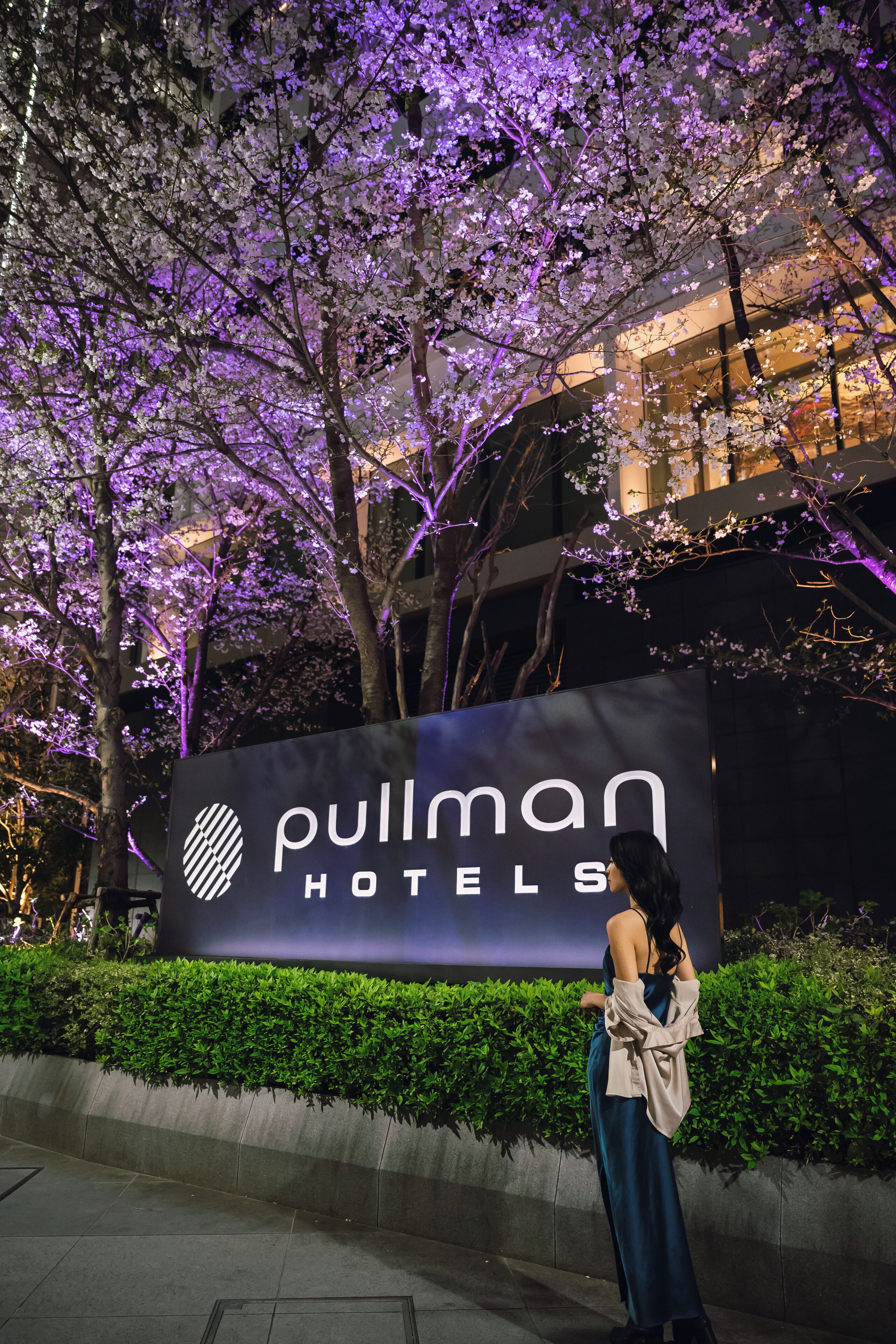 Ein Hotelschild mit dem Schriftzug "Pullman Hotels" und eine Frau, die davor steht.