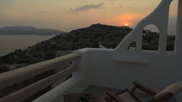 Un balcón con vistas a la puesta de sol sobre un paisaje montañoso.