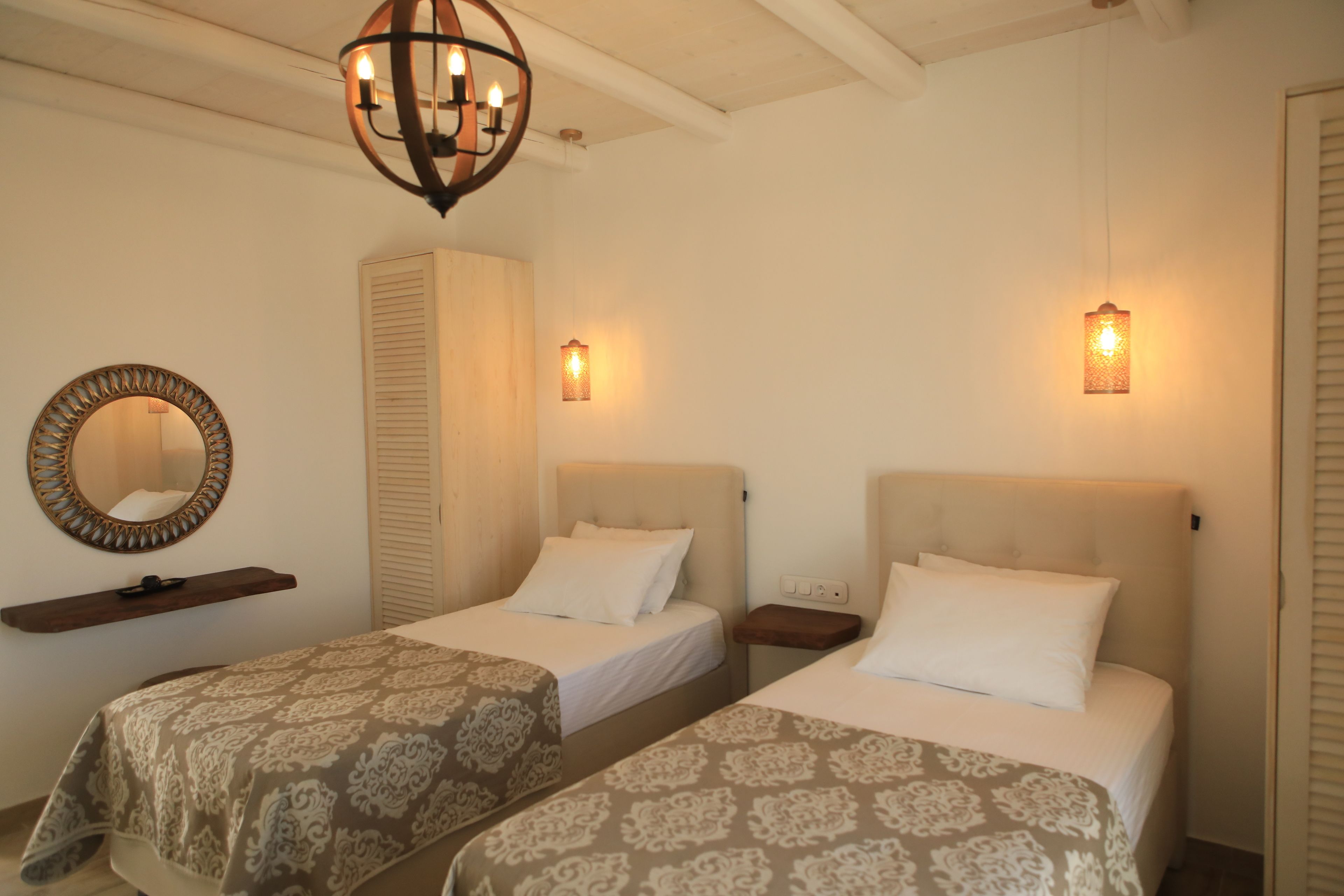 Una habitación de hotel con dos camas, un espejo, una repisa y una lámpara colgante.