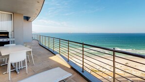 A balcony with a view of the ocean, a table, and chairs. - Horizon Bay 1602 (Cape Town)