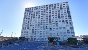 A tall, modern apartment building with a uniform facade and multiple windows. - Blouberg Heights 202 (Cape Town)