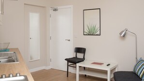 A modern, minimalistic room with a kitchenette, a dining area, and a seating space.