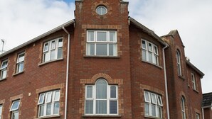 A red brick building with multiple windows and a central circular window.