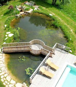 Une terrasse en bois avec un espace de détente circulaire et une piscine.
