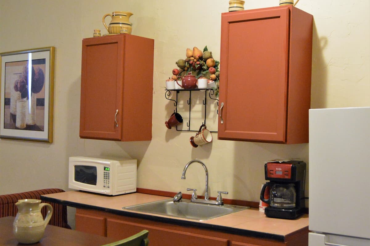 A compact kitchen with wooden cabinets, a microwave, a coffee maker, and a sink.