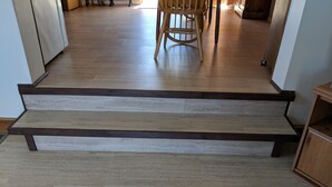 A set of wooden steps leading to a room with a wooden floor and a chair in the background. - Lakefront Cottage w/Breathtaking Views! Hiking.PaddleBoat.Doc.Fishing.WiFi (Wells)