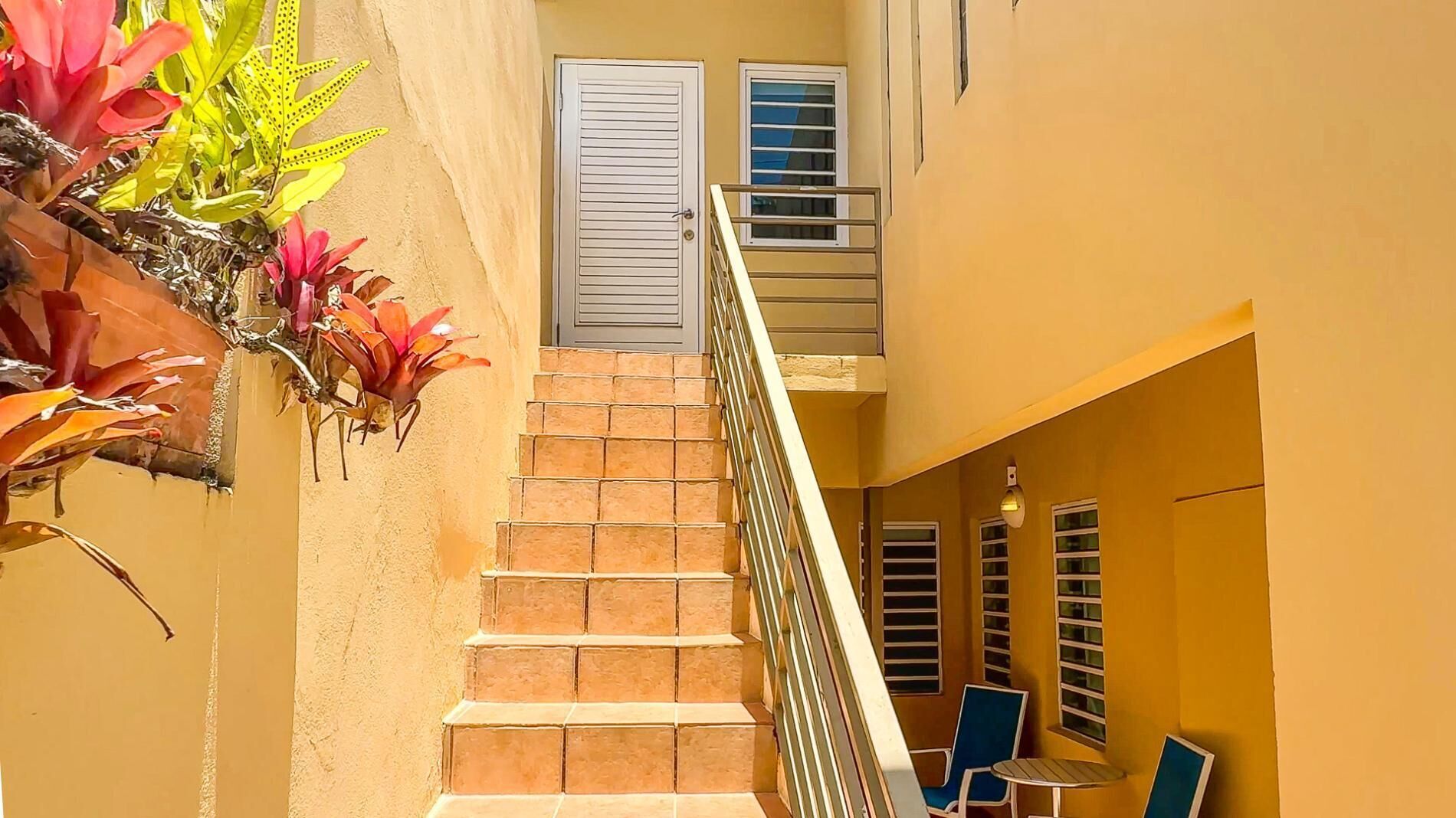 A staircase leading to a balcony with a view of the sky, a small table, and a chair.