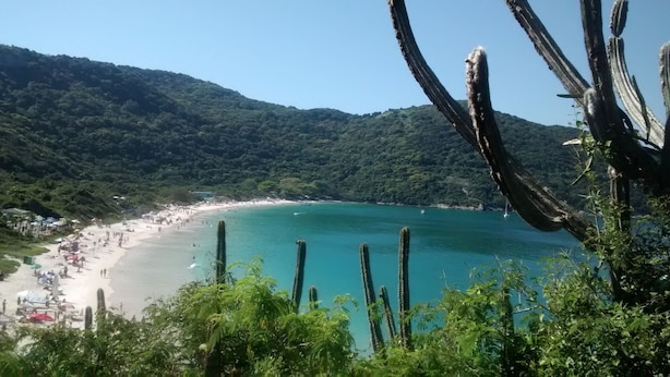 A beach with clear turquoise waters, surrounded by lush green hills. - Family apartments - air conditioning, fan, internet... fully furnished. (Arraial do Cabo)