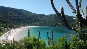 A coastal landscape with a beach, clear turquoise waters, and a forested hillside. - Family apartments - air conditioning, fan, internet... fully furnished. (Arraial do Cabo)