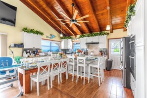 Una cocina amplia con vigas de madera, armarios blancos y una isla central con asientos.